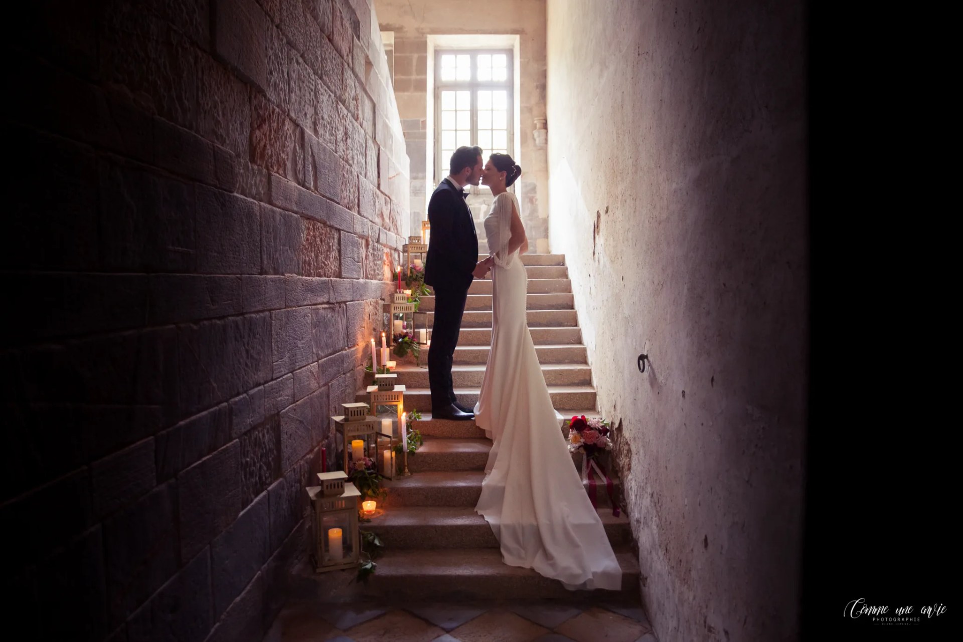 Les mariés enlacés dans l'escalier de pierre, bordé de bougies