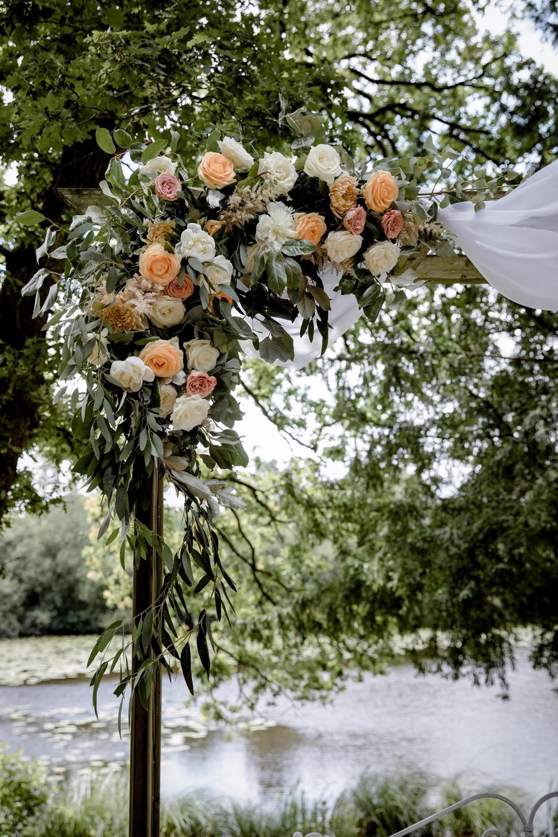 Arche florale aux tons pêche, dressée au bord de l'eau