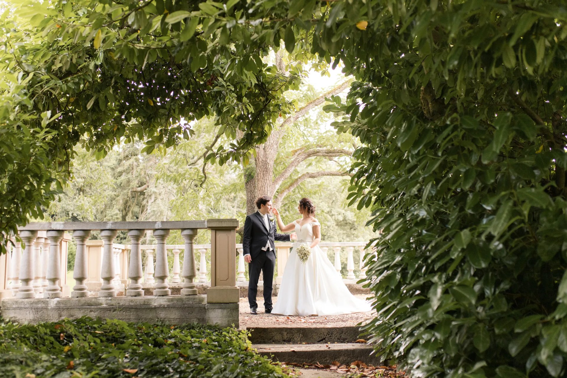 Les mariés sur la terrasse à balustrade, sous la verdure