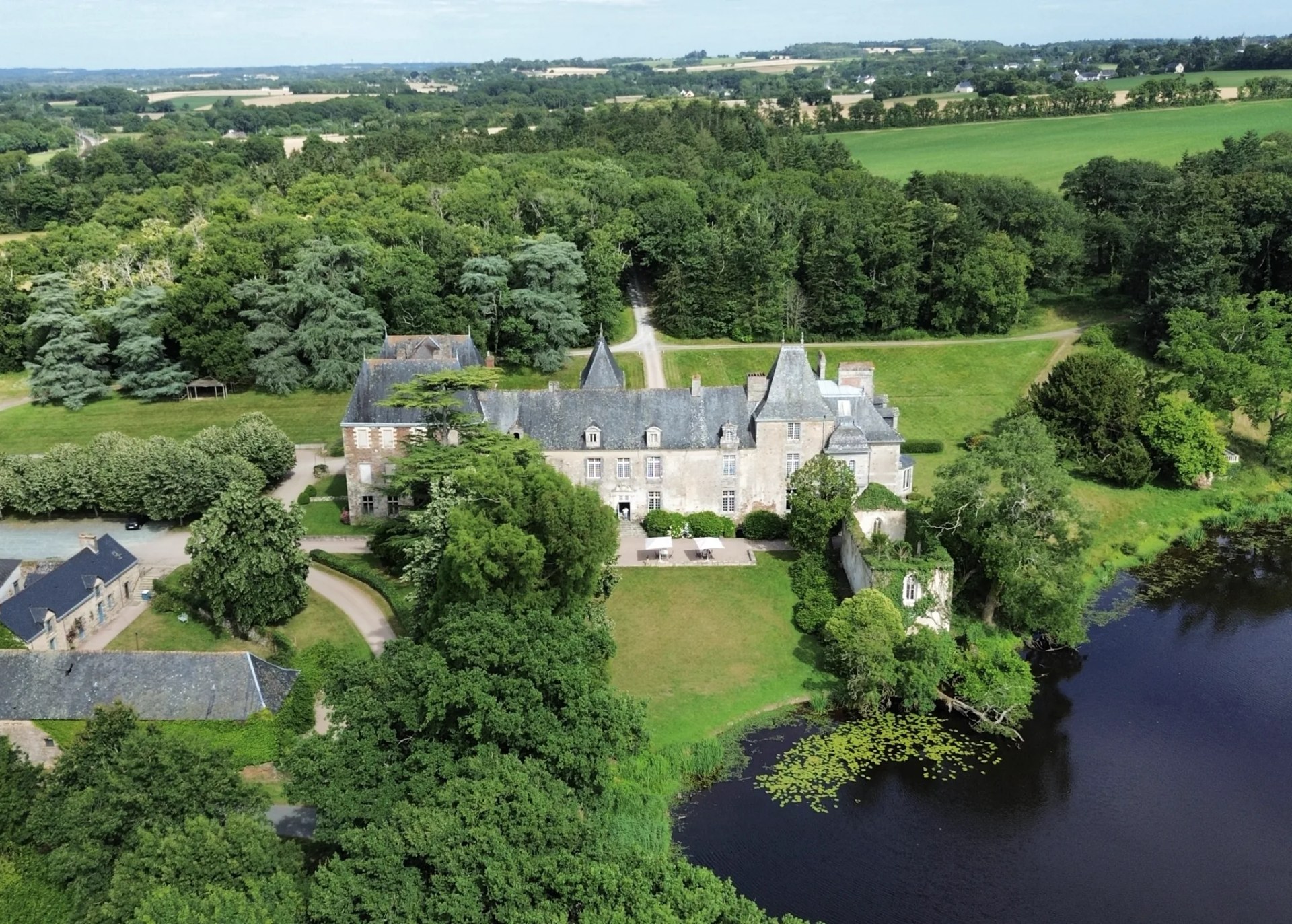 Aerial view of Château du Pordor, its park of century-old trees and the lake, in the heart of the Breton countryside