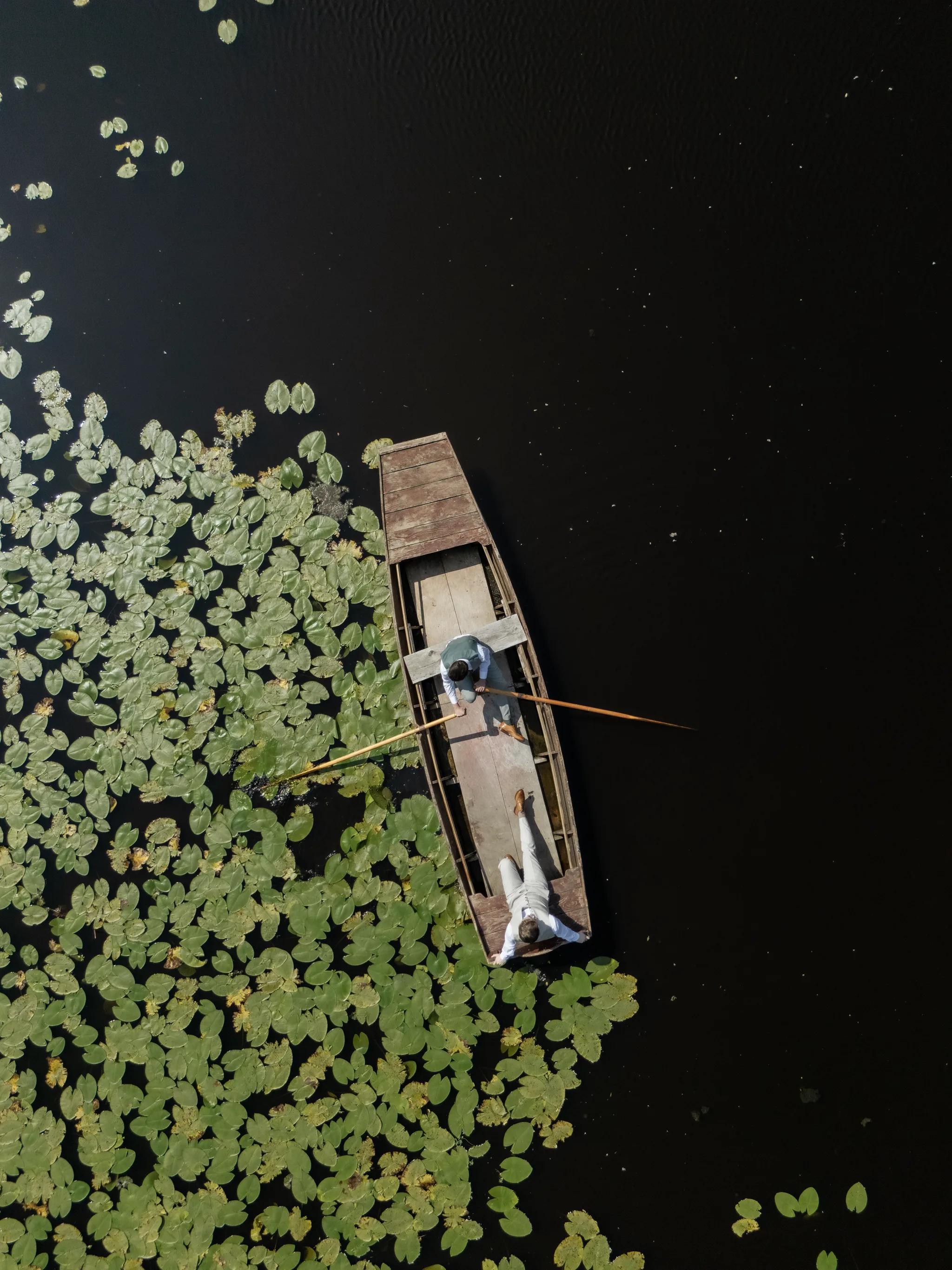 Overhead drone view: a wooden rowing boat on the water-lily lake