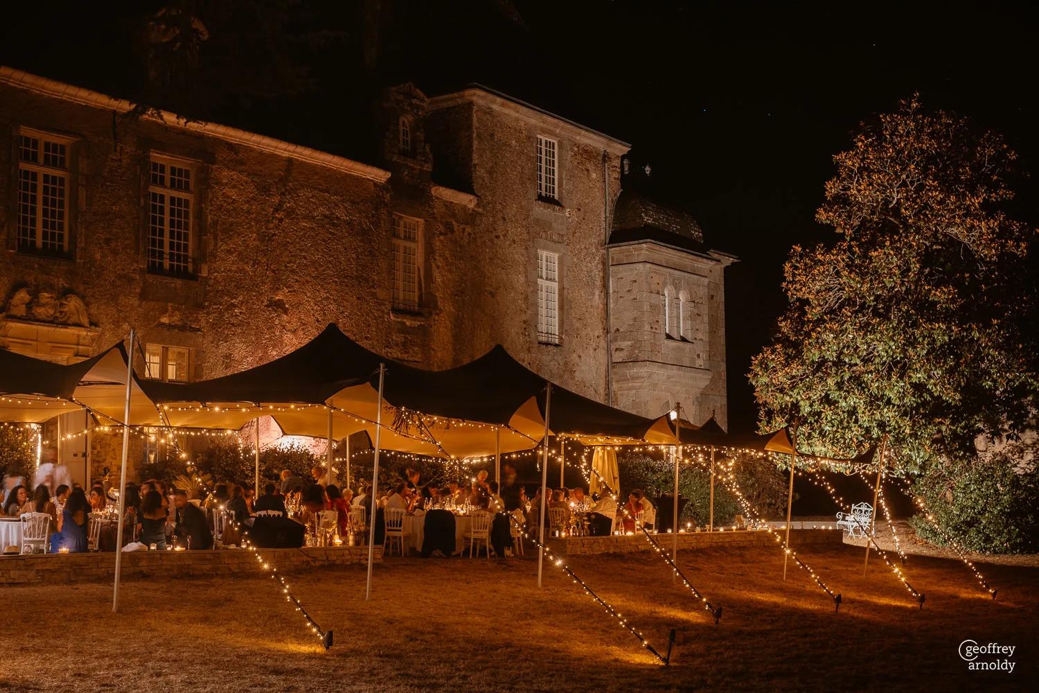 Dinner set outdoors under strings of lights, at nightfall