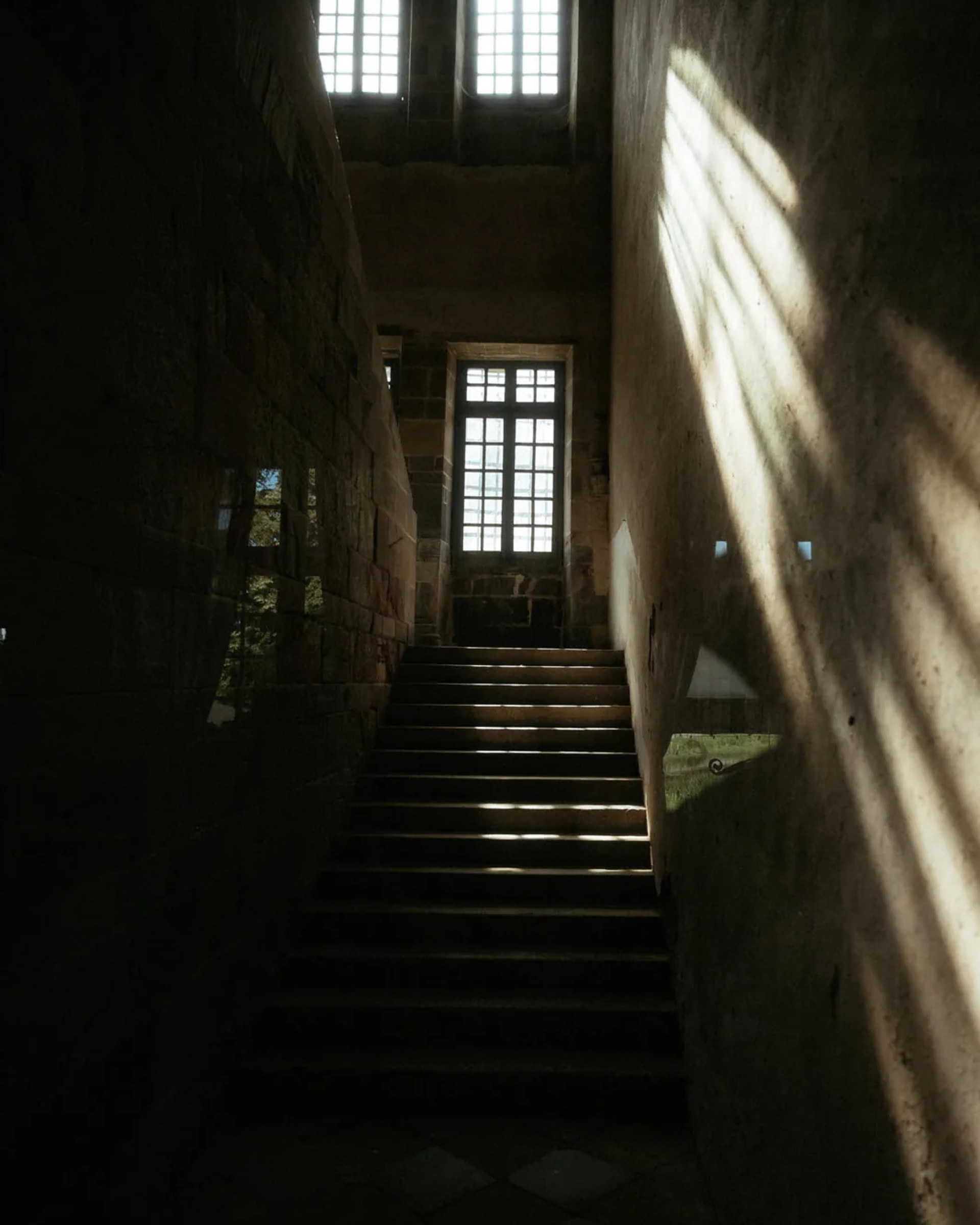 L'escalier de pierre du château, éclairé par une fenêtre à meneaux