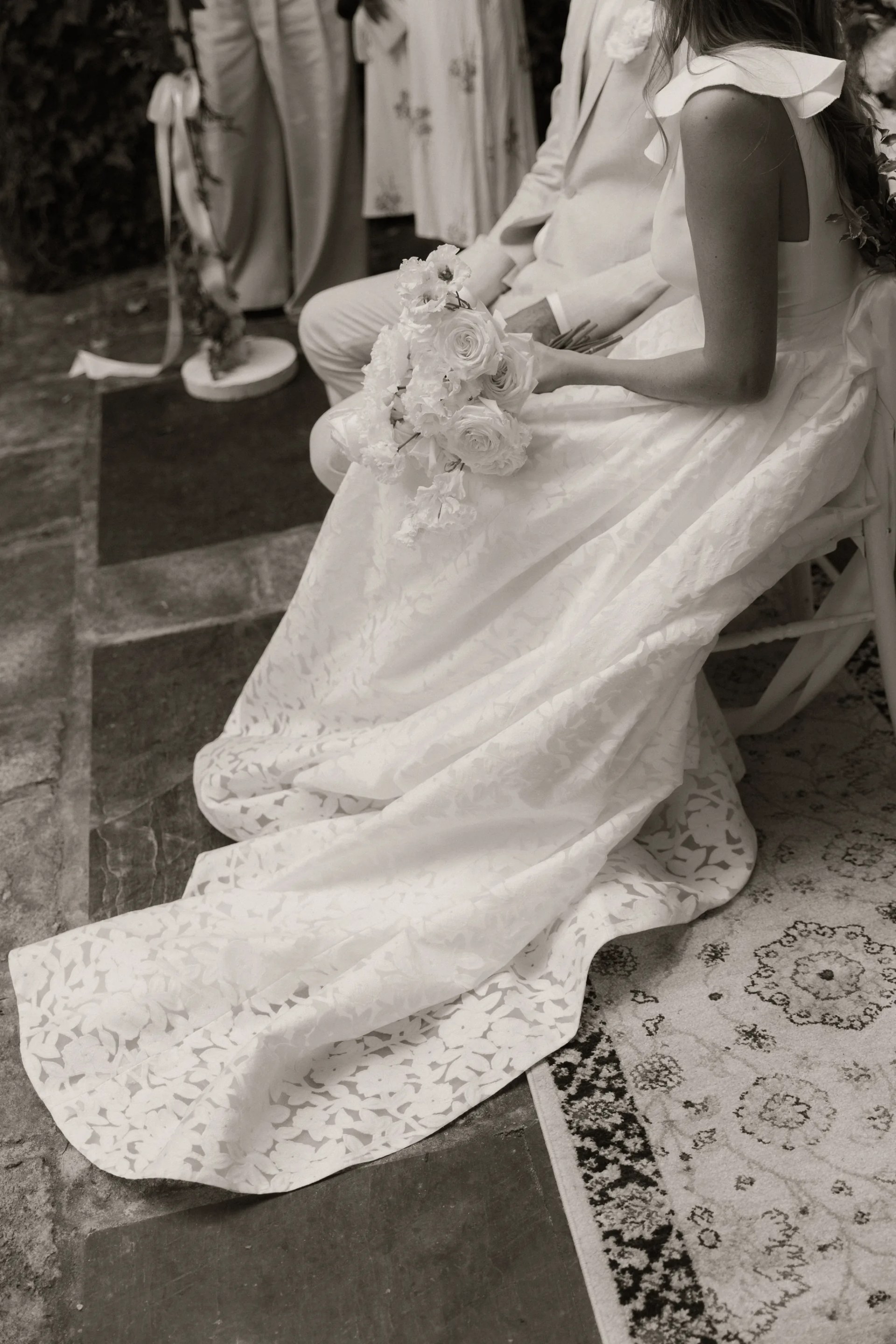 Détail de la traîne de dentelle et du bouquet de roses blanches