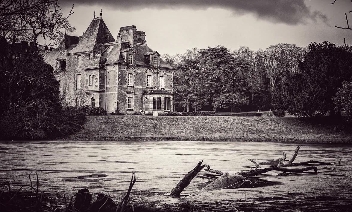 Le château en noir et blanc, vu depuis la rive de l'étang