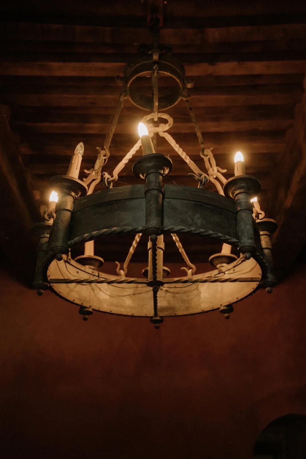 Un lustre en fer forgé sous les poutres anciennes