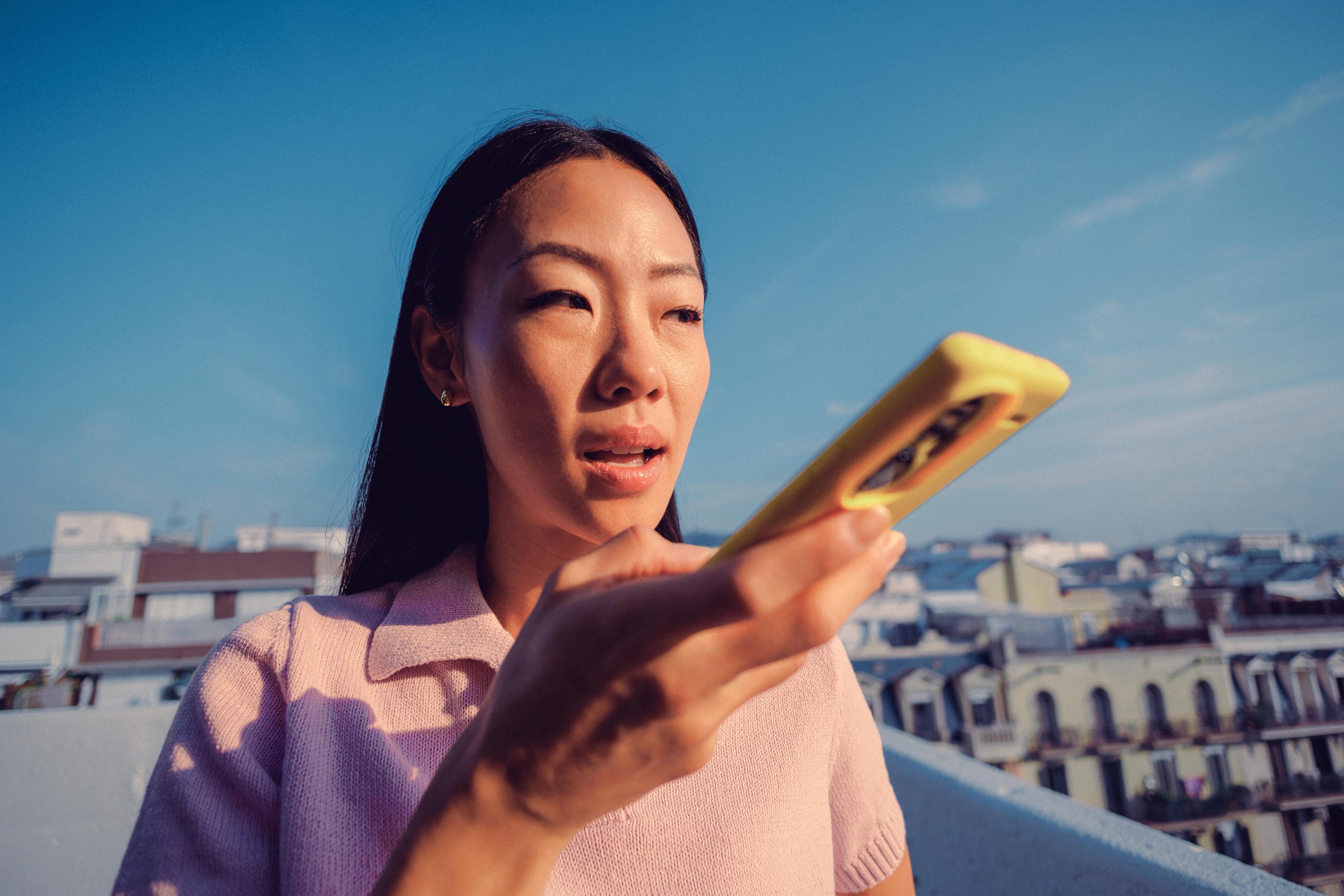 Woman speaking into her phone on a rooftop above the city