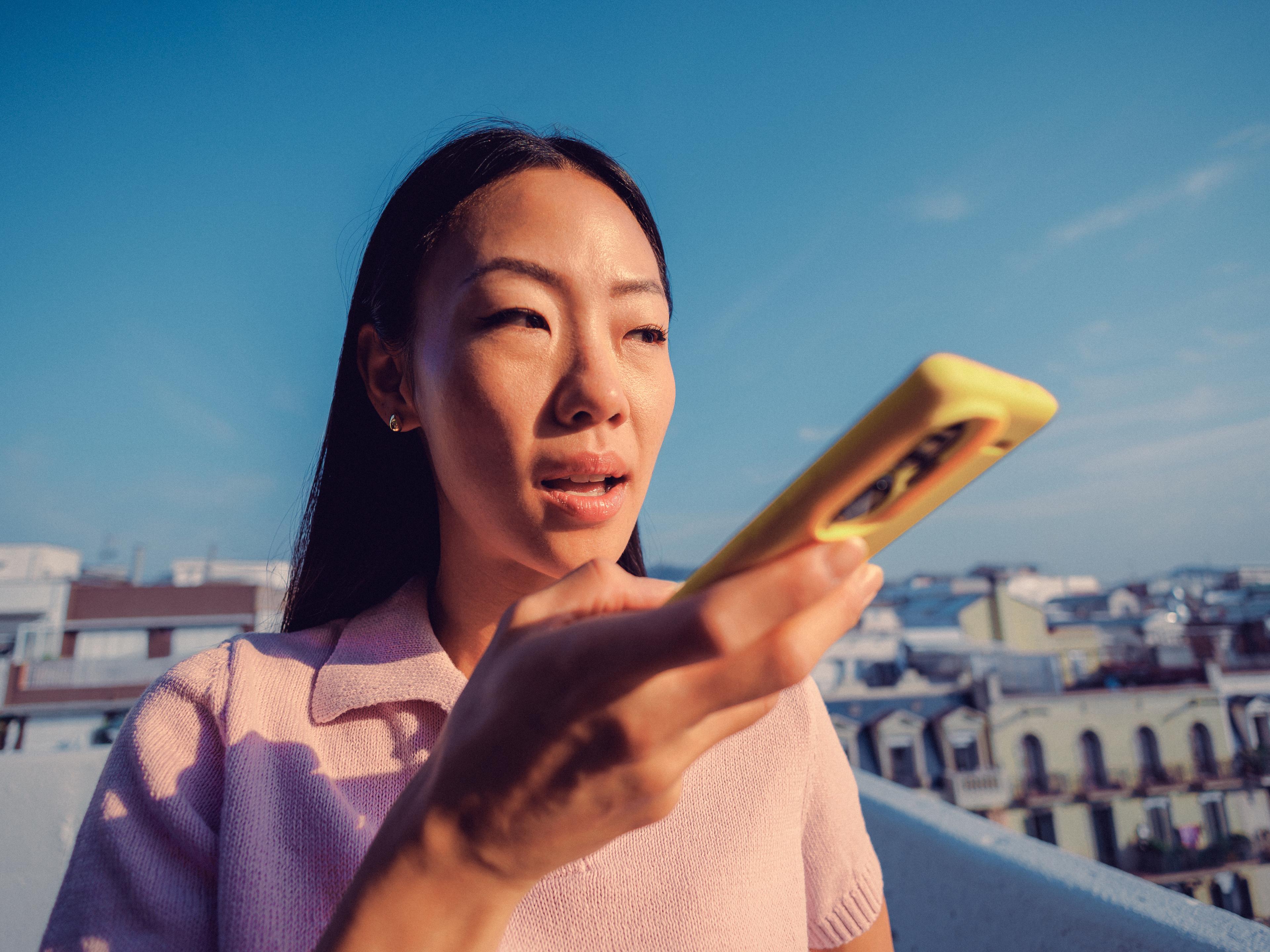 Woman speaking into her phone on a rooftop above the city