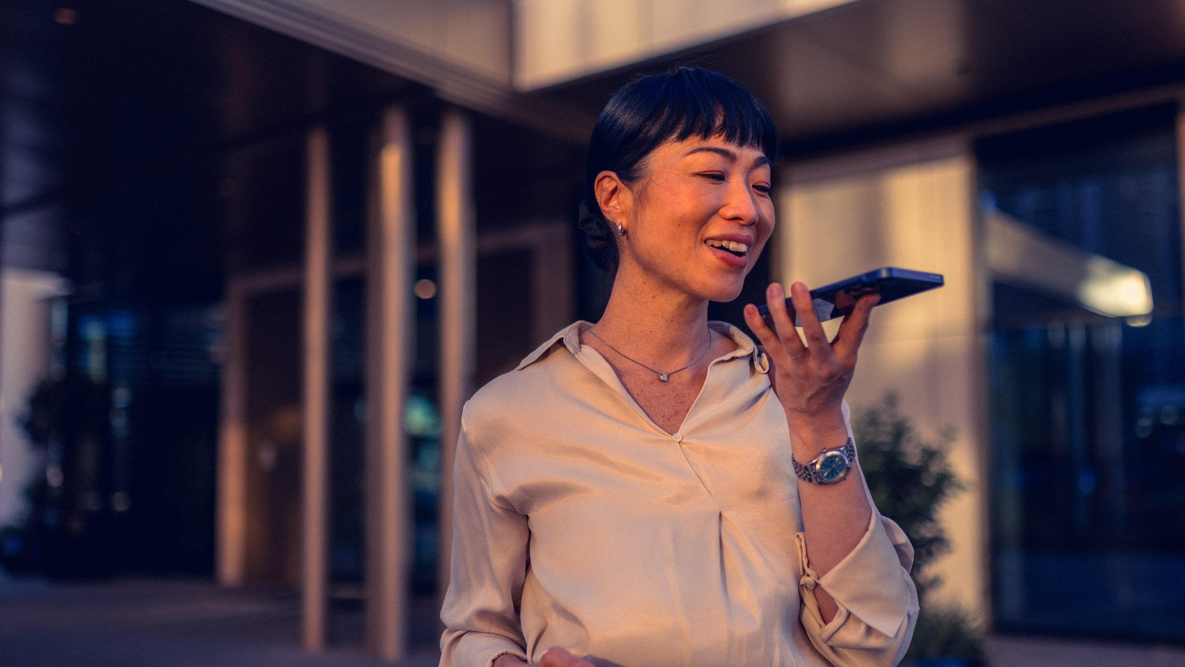 Woman in the city speaking into her phone, wearing earbuds