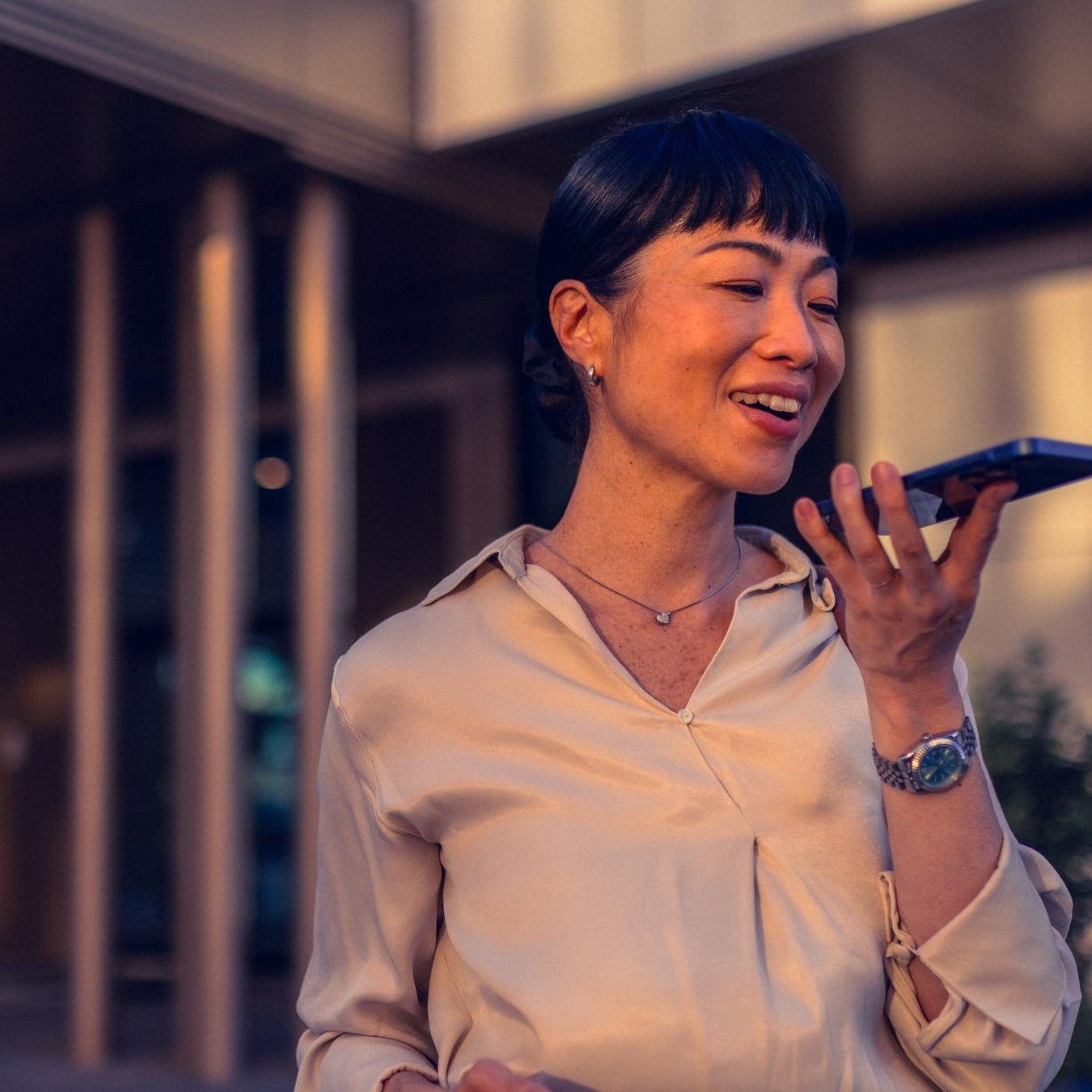 Woman in the city speaking into her phone, wearing earbuds