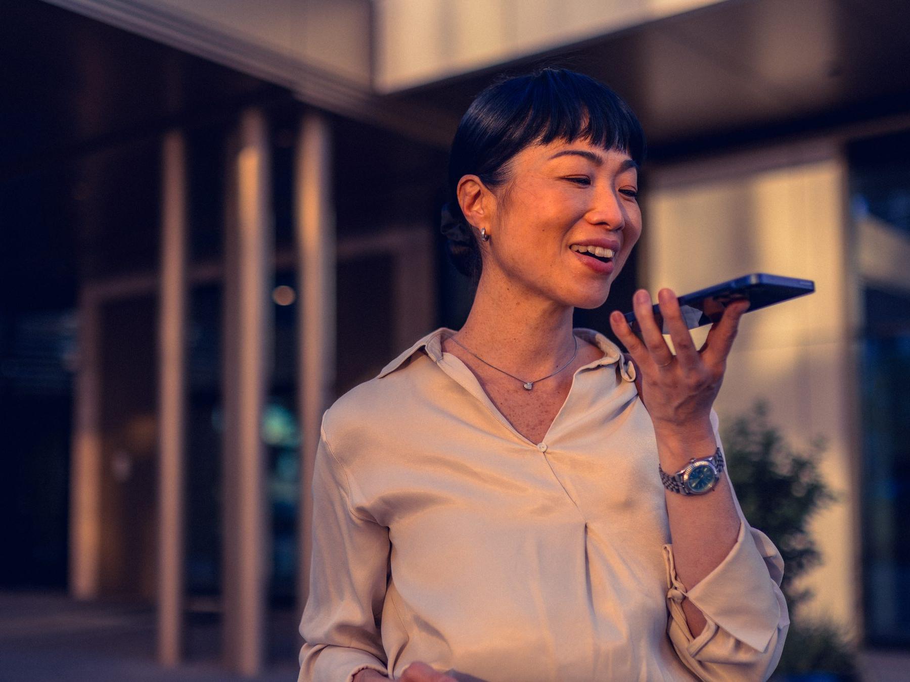 Woman in the city speaking into her phone, wearing earbuds