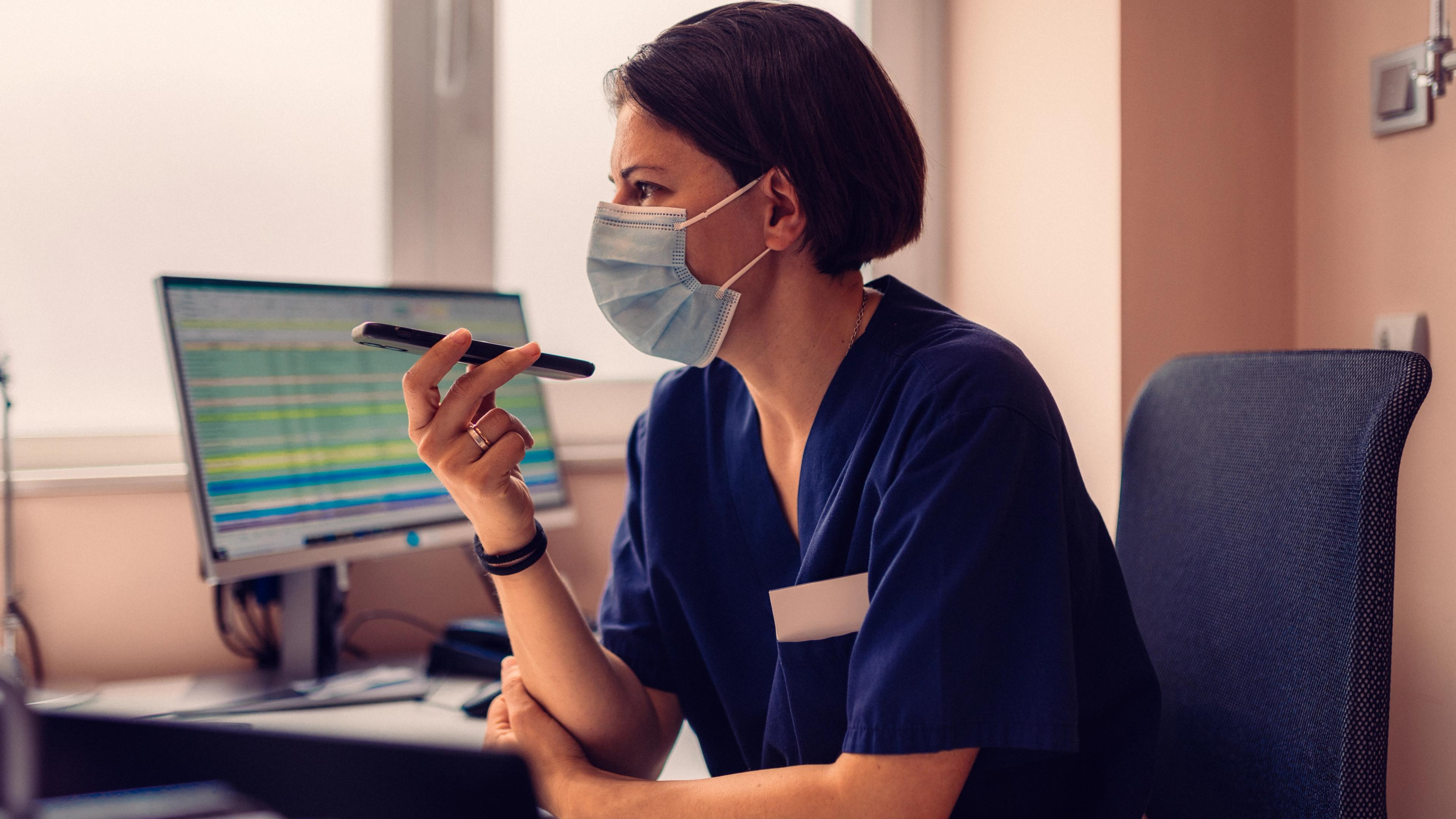 Medial professional talking on phone on speaker with a mask on