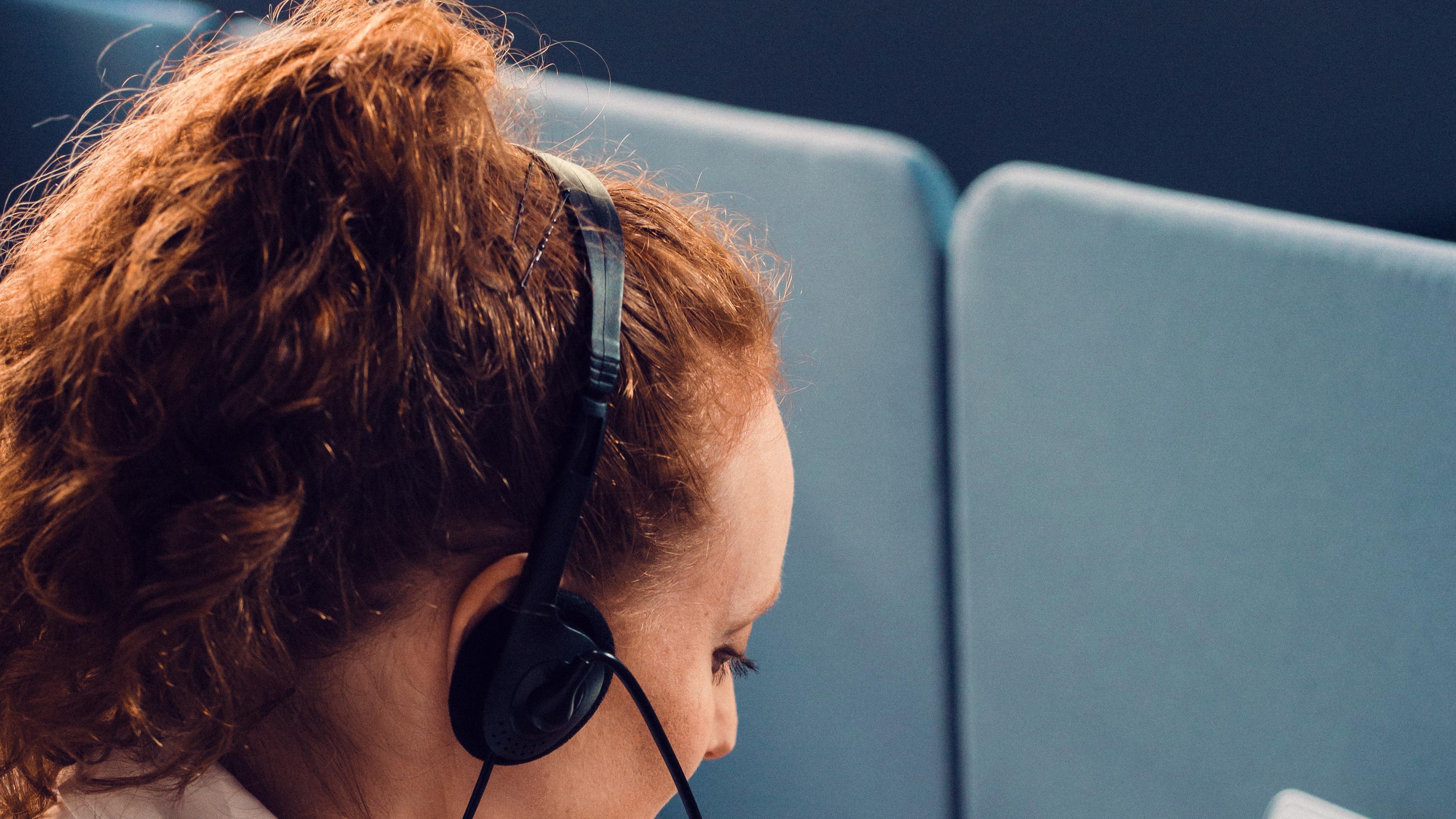Woman in a headset typing on a laptop
