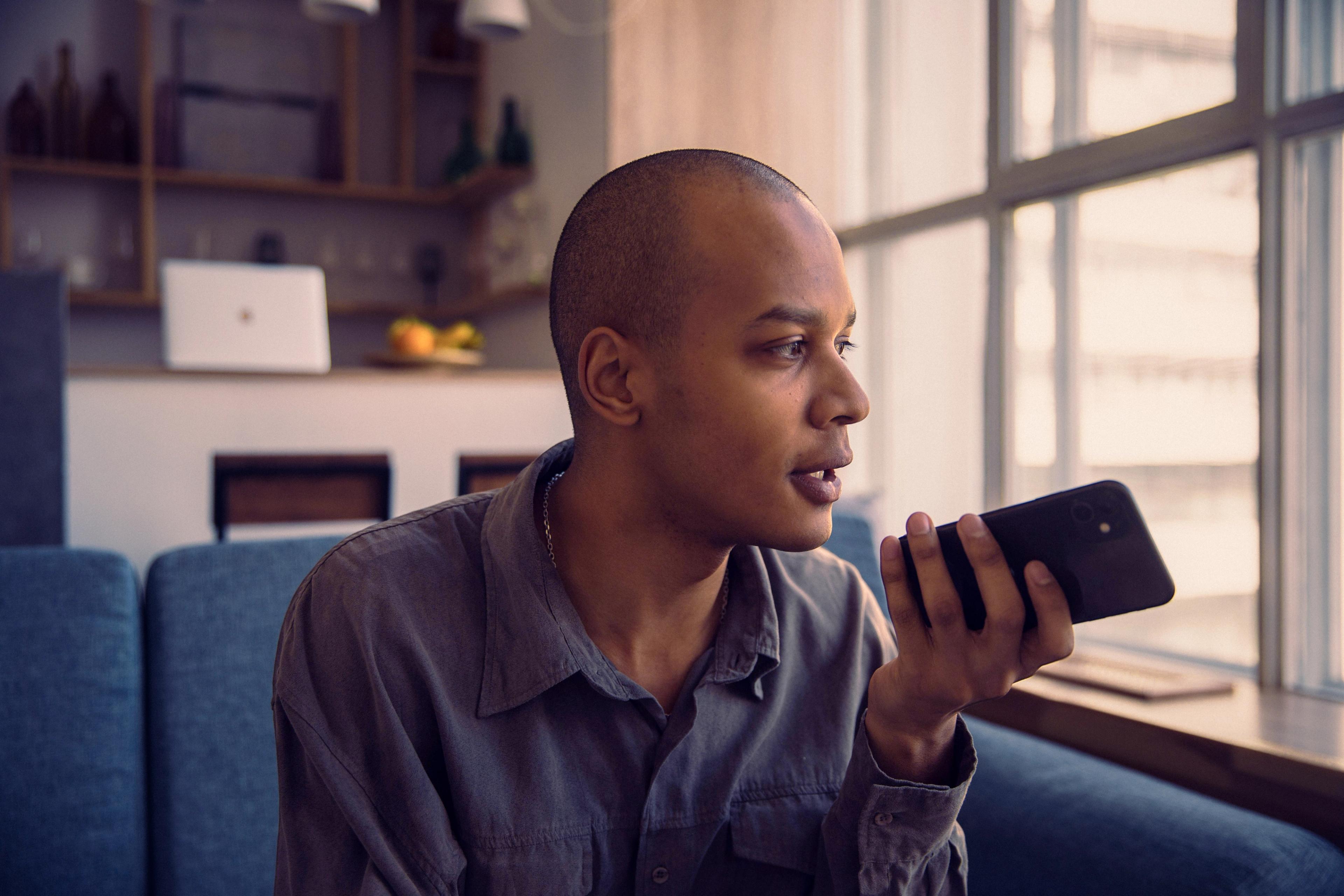 Man on a sofa speaking into his phone