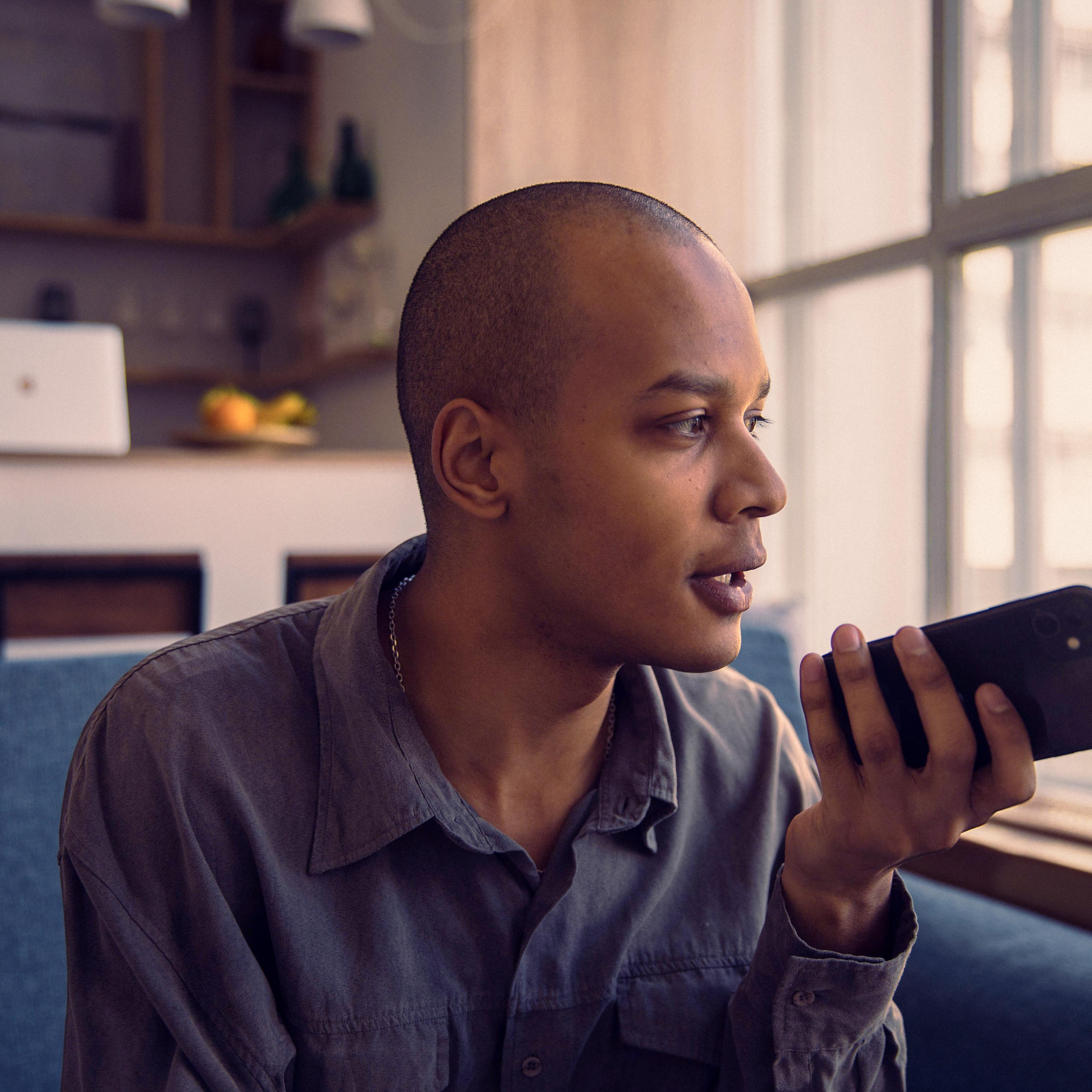 Man on a sofa speaking into his phone
