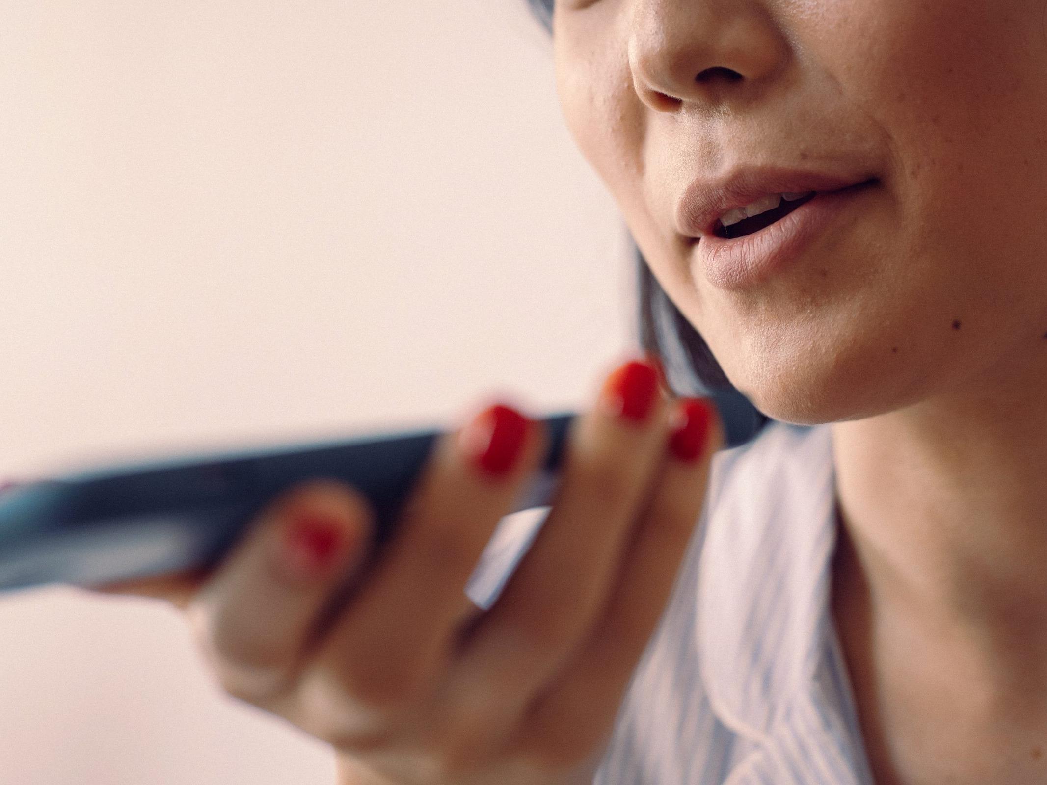 Woman speaking into a phone held close to her face