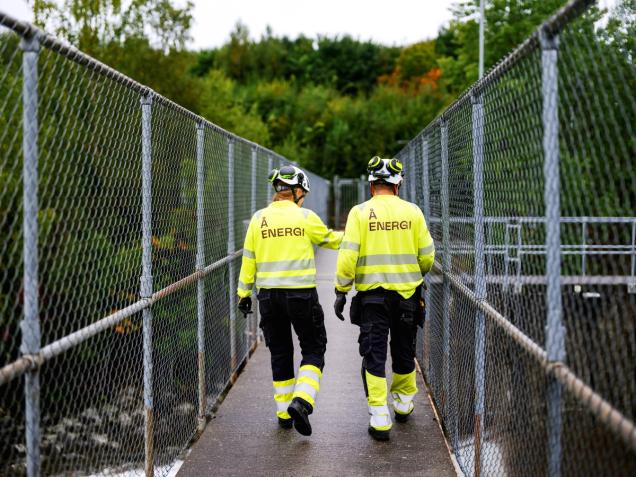 To personer går i anlegg med arbeidsklær - på stasjon