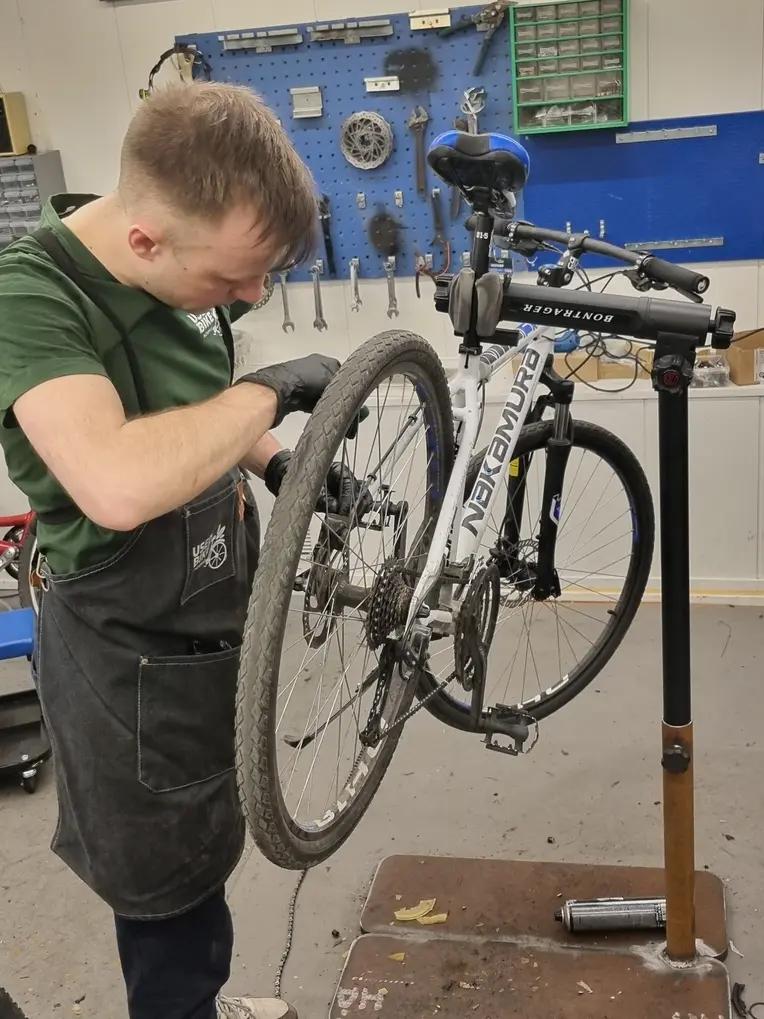 En ung gutt mekker på sykkel i et verksted