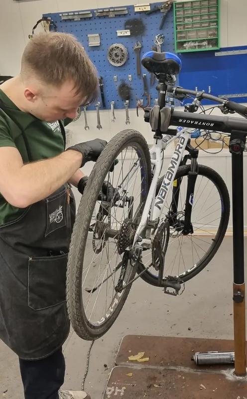 En ung gutt mekker på sykkel i et verksted