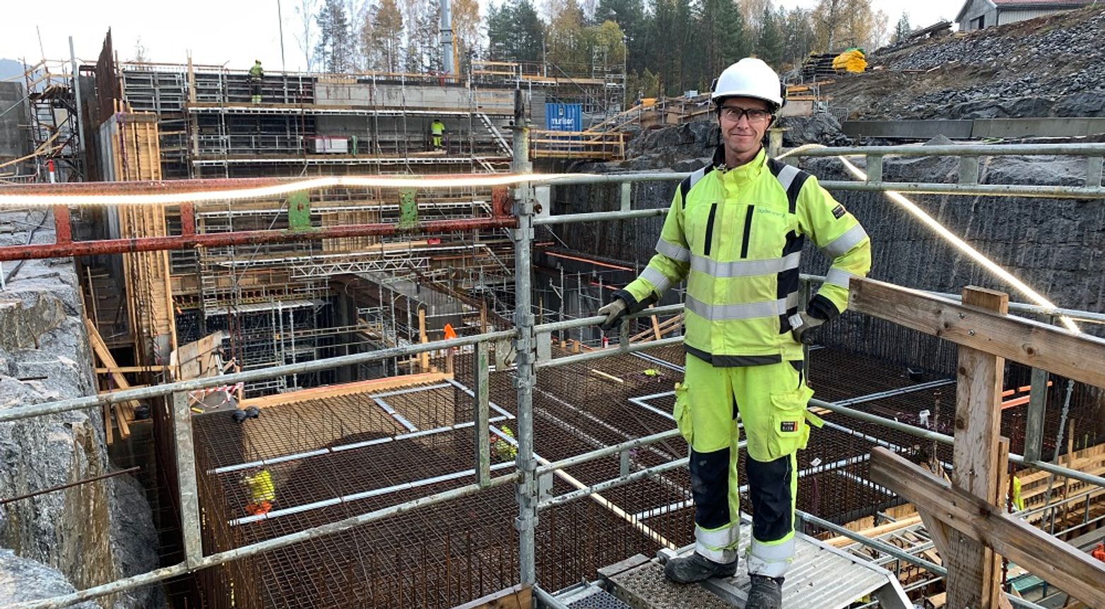 Mann iført arbeidstøy på byggeplass.
