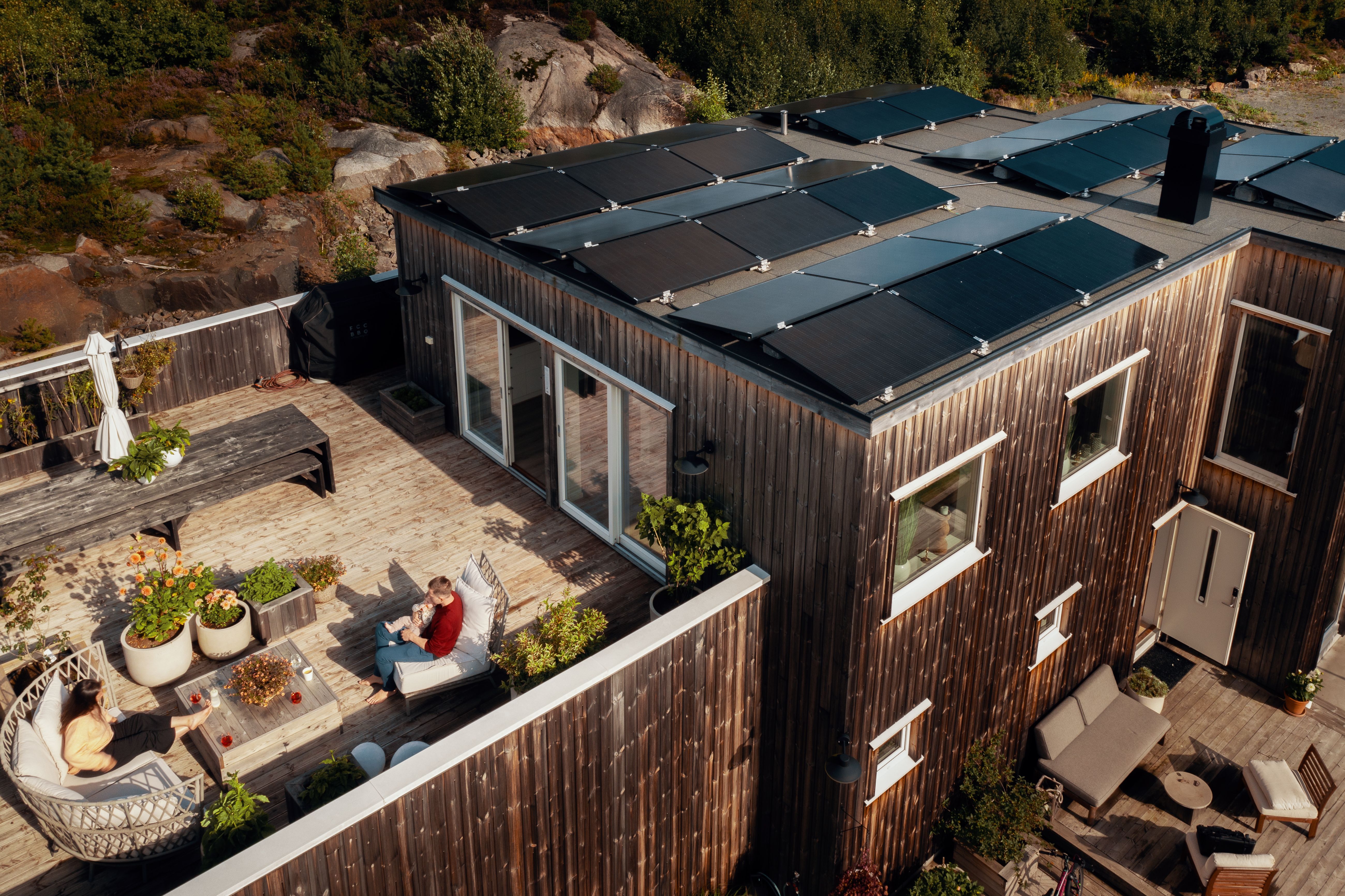 Moderne hus med solceller og beboere på balkongen.