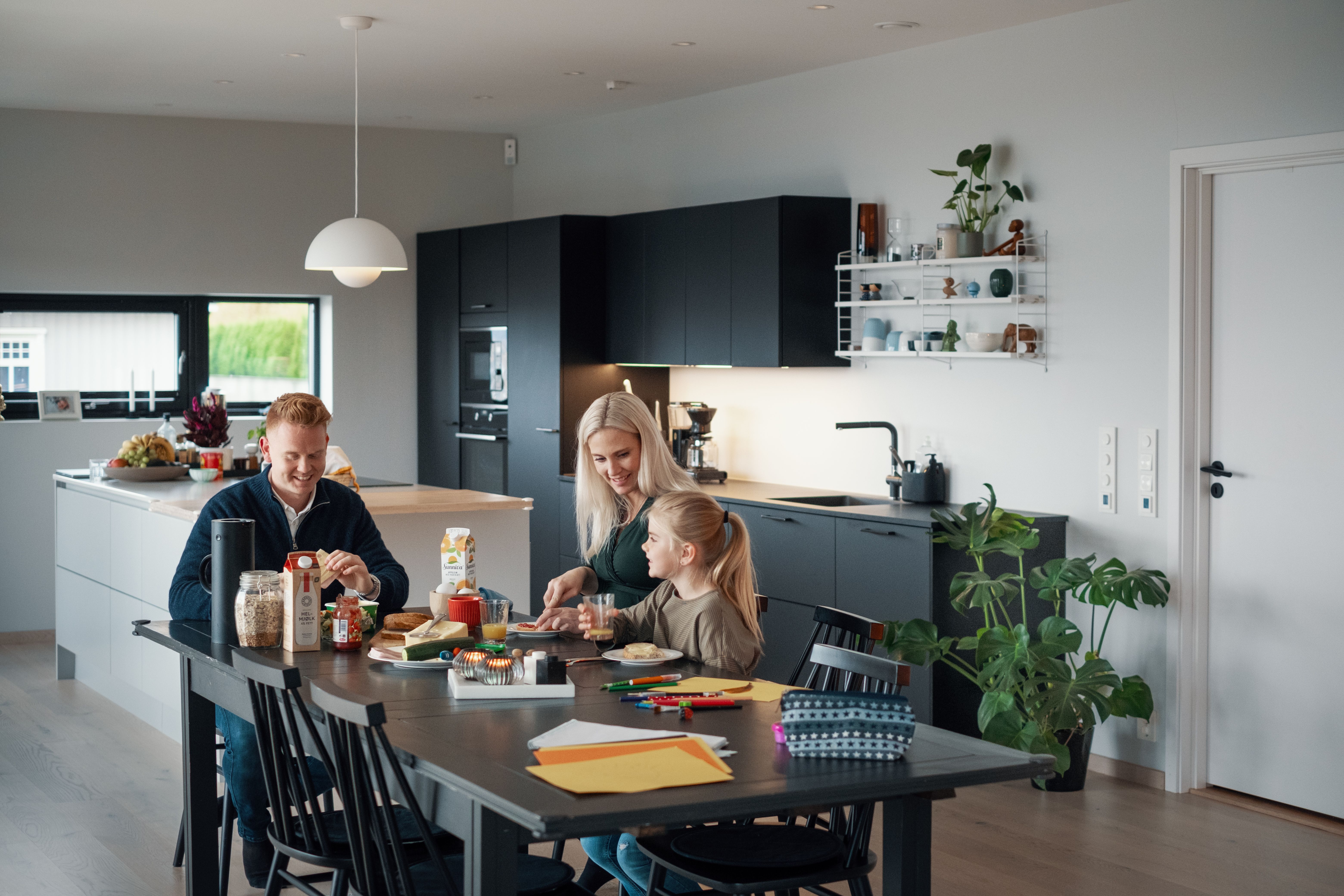 Familie som sitter ved kjøkkenbord og spiser frokost