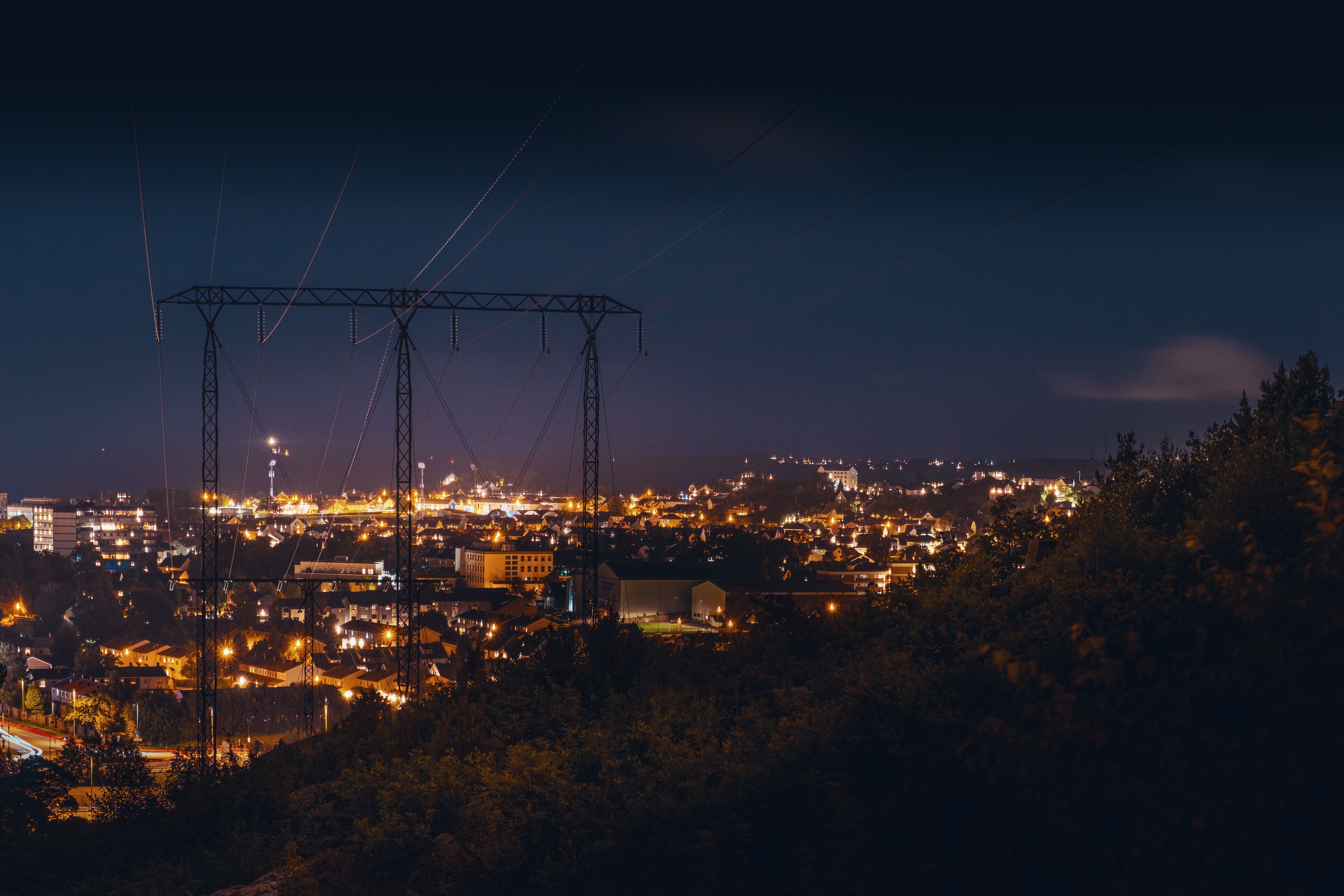 Bilde av mast med en lysende by på kvelden