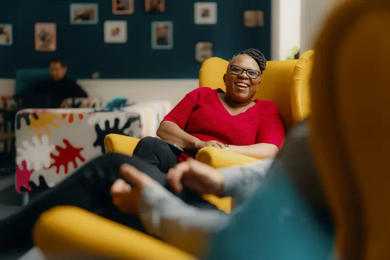 Carer sat chatting, laughing in an armchar