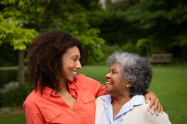 Carer embracing elderly woman outside