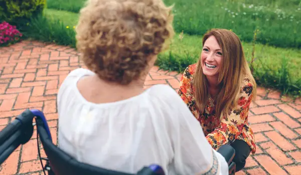 Young woman caring for elderly woman in wheelchair