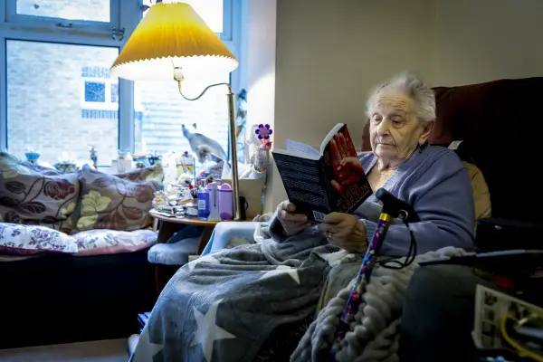 Elderly woman reading a book in her living room