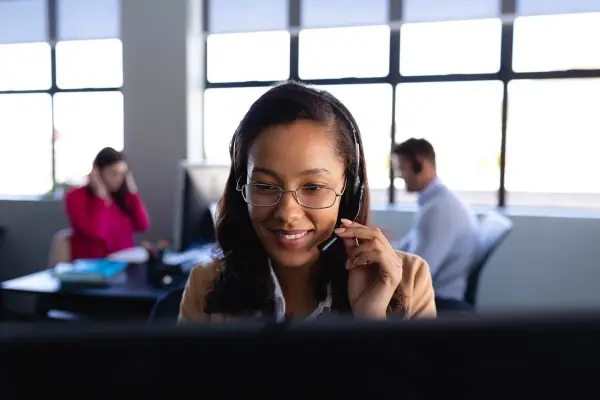 A woman answering a call while holding her headphones