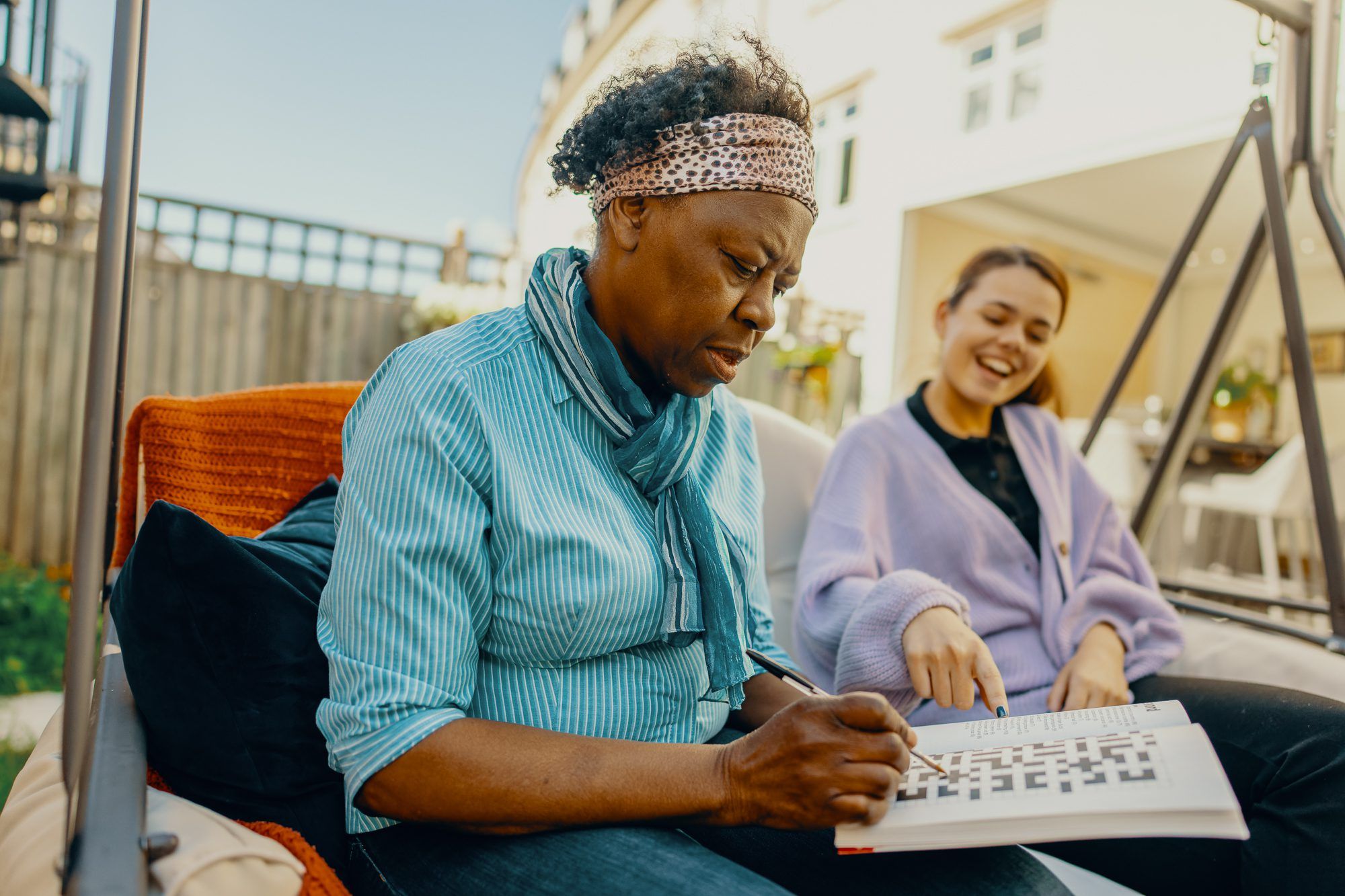 A carer is helping a care recipient fill in a crossword.