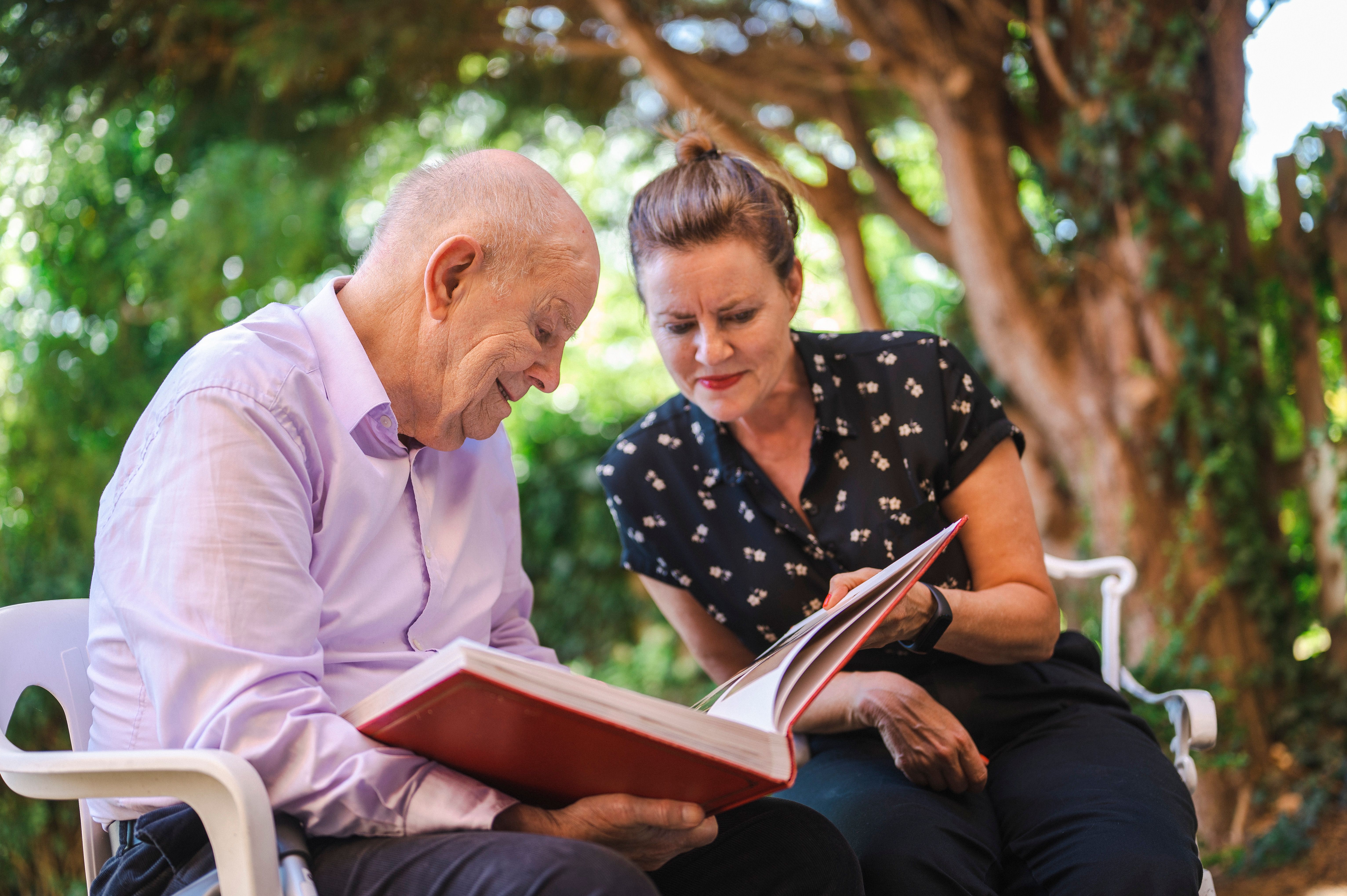 A carer showing an elderly man a picture book