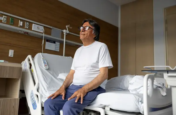 Elderly man sitting on hospital bed