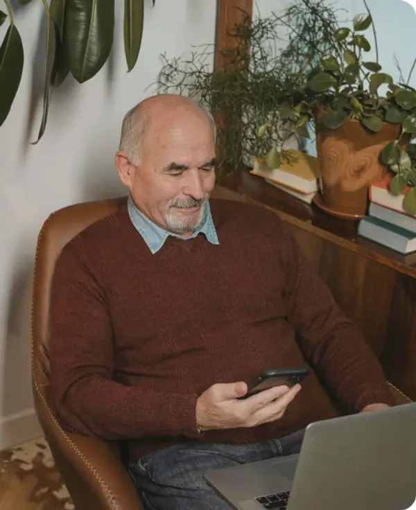 Elderly man with his phone and laptop