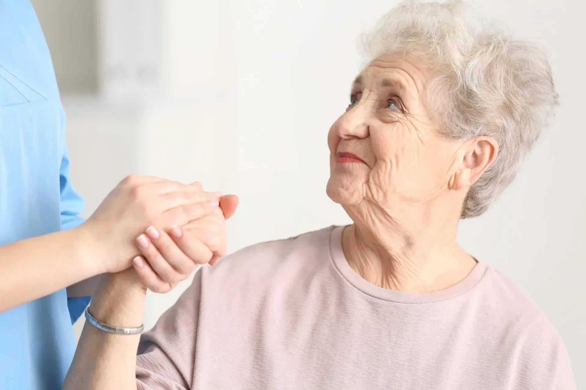 Carer holding hands with elderly woman