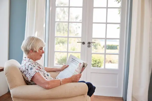 Woman sitting in an armchair reading a newspaper