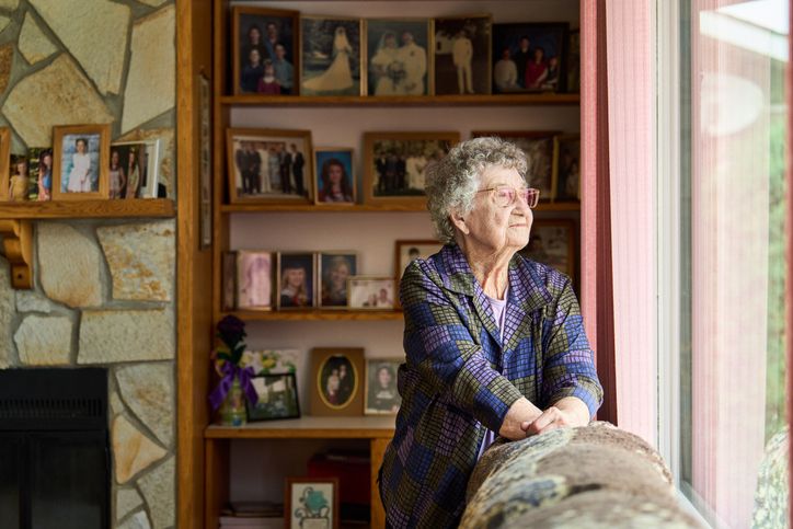 Elderly woman looking outside the window
