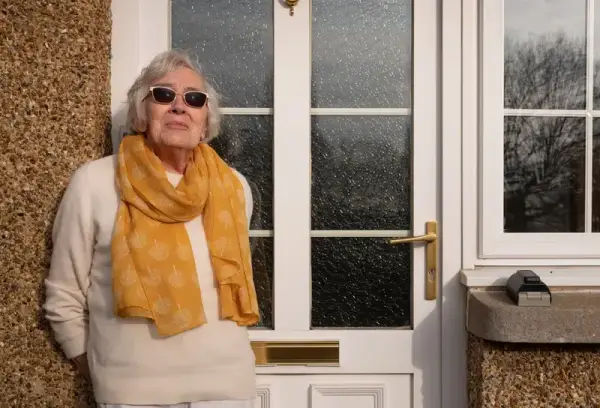 Elderly woman standing by her front door