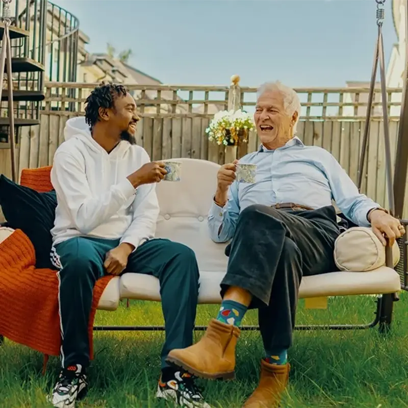 Elderly man having a cup of tea with his carer in the garden