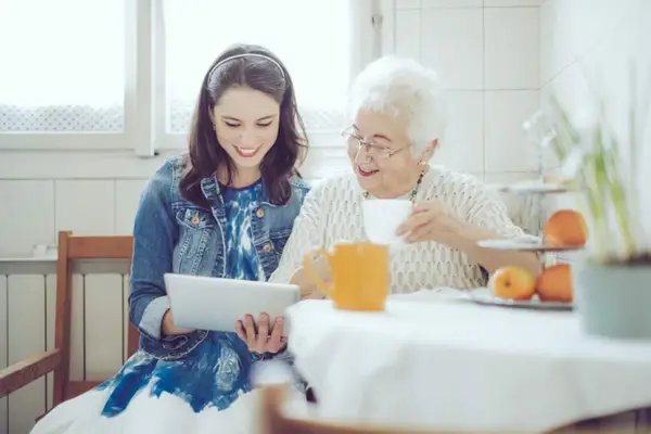 Elderly woman looking at tablet with her carer