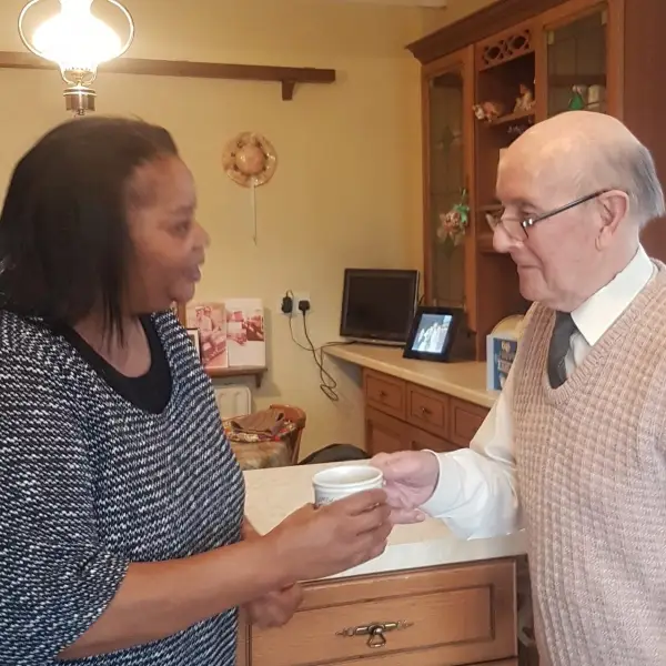 Elderly man and carer drinking tea