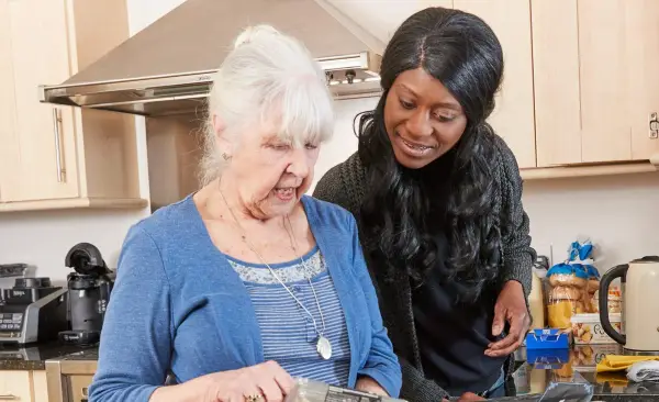 Carer helping elderly woman in the kitchen