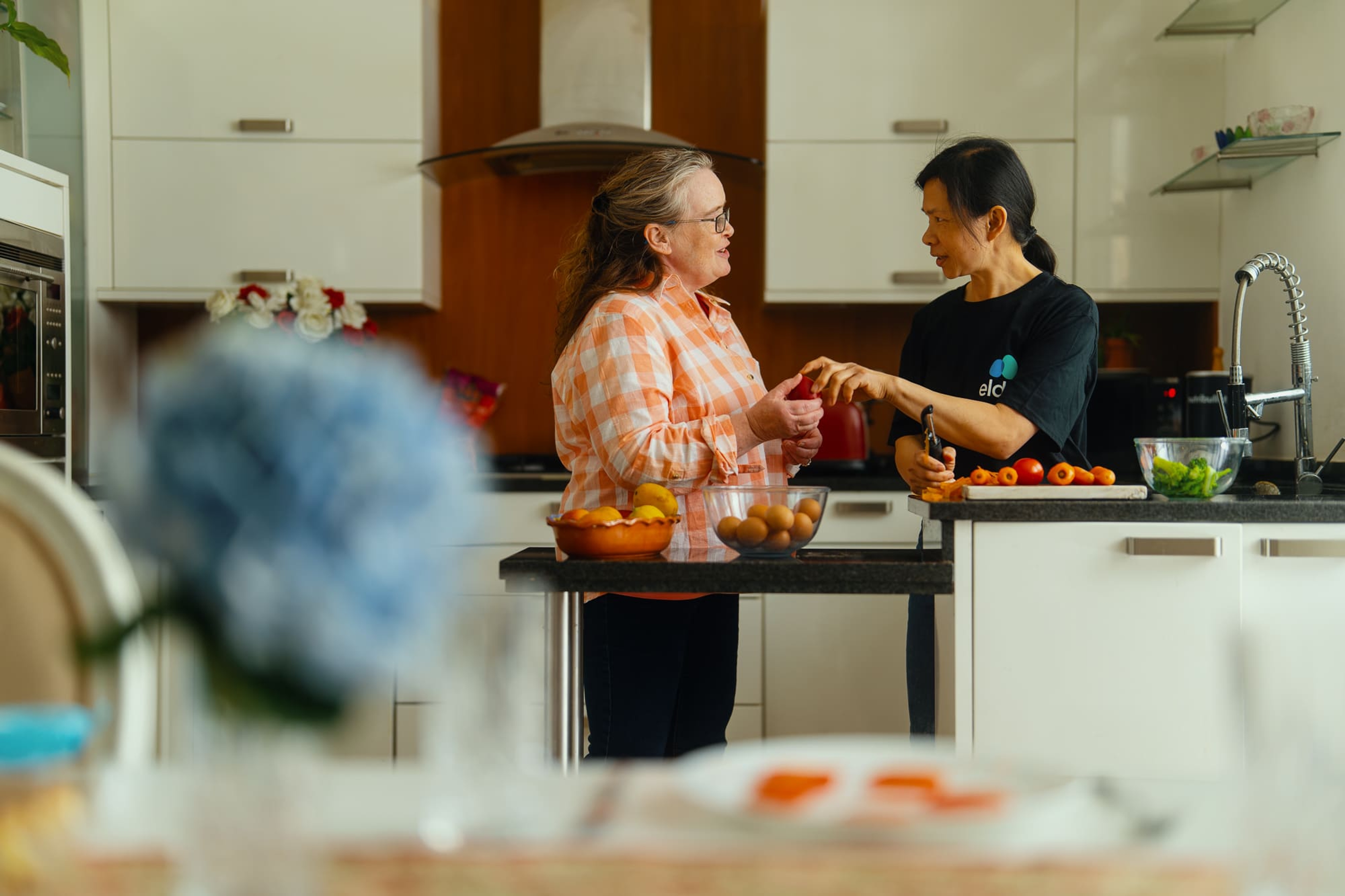 A live-in carer and a customer talking in the kitchen of her home