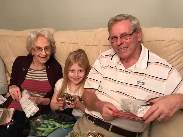 Jean and John opening Christmas gifts with their granddaughter