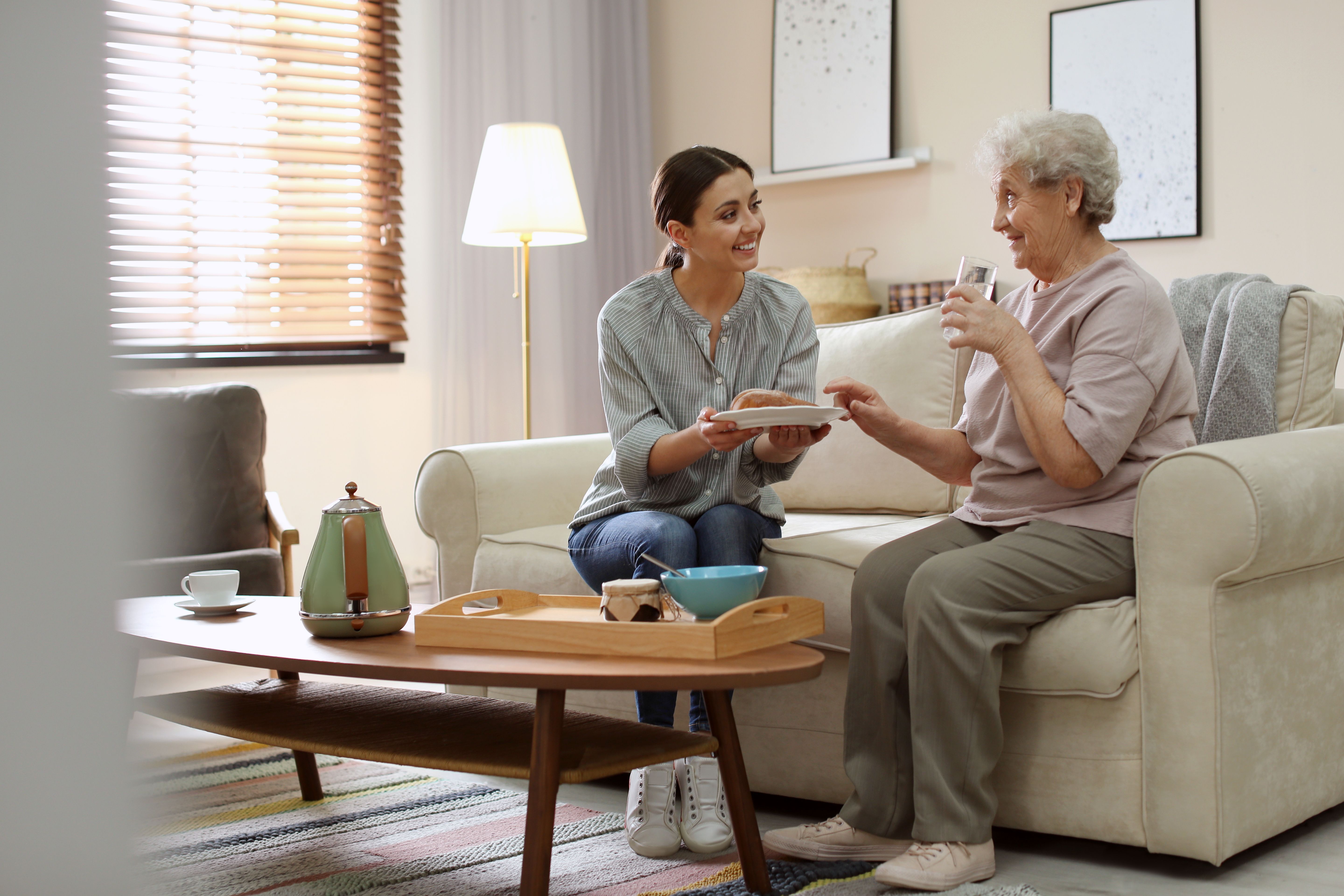 A carer offering an elderly woman food 