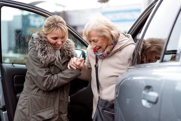 Carer helping an older woman get out of the car