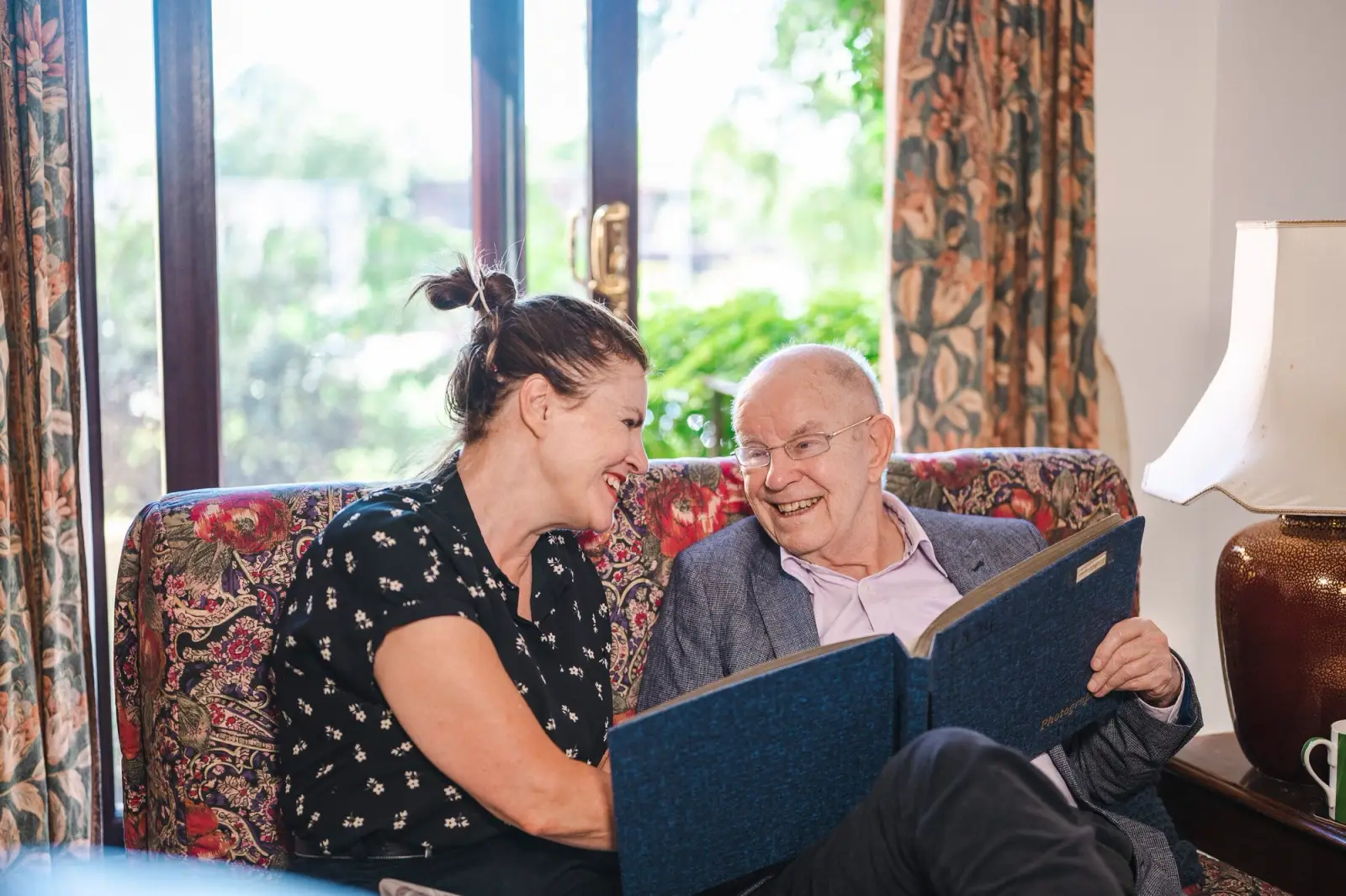 Elderly man reading a book with his carer