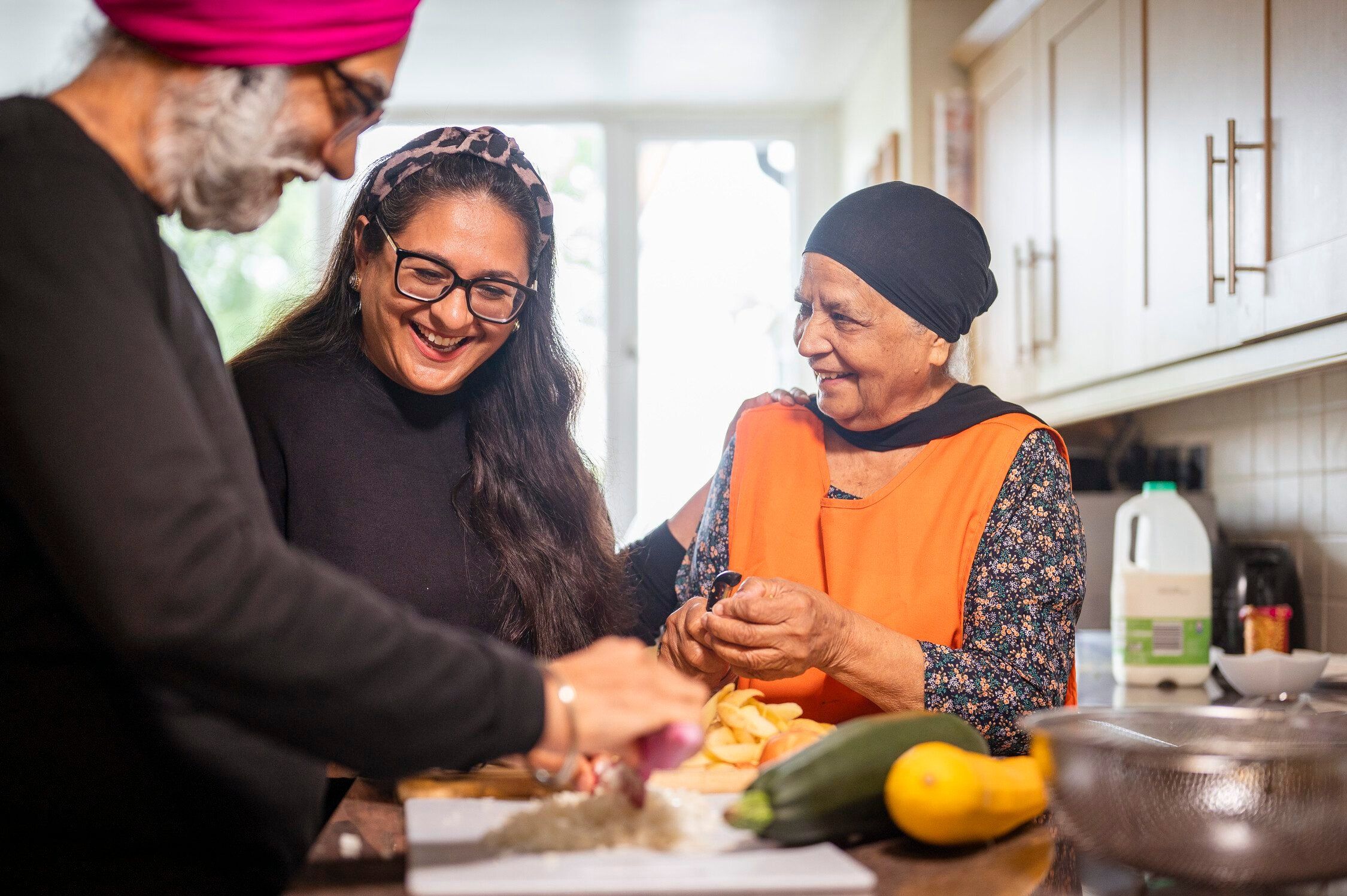 Carer in the kitchen supporting elderly couple
